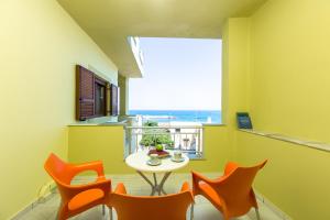 a dining room with orange chairs and a table and a window at Glaros in Panormos Rethymno