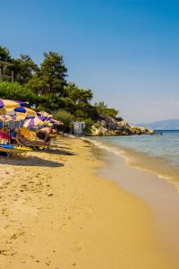 a sandy beach with umbrellas and the ocean at Hotel Villa Nisteri in Limenas