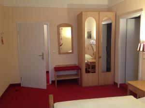 Schlafzimmer mit einem Bett, einem Spiegel und einer Tür in der Unterkunft bei Zwillings Hotel & Restaurant in Hilbersdorf