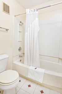 a white bathroom with a toilet and a bath tub at Red Carpet Inn - Louisville in Louisville