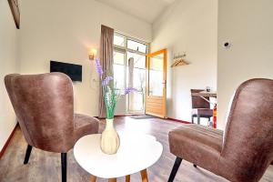 una sala de estar con 2 sillas y un jarrón sobre una mesa en Tussen de Diepen en Blokzijl