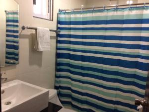 ein Bad mit einem Duschvorhang und einem Waschbecken in der Unterkunft Mañana Hotel in Olongapo