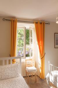 MontolieuにあるGite de Mallastのベッドルーム1室(オレンジ色のカーテン、ベッド1台、窓付)