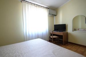 a bedroom with a bed and a desk with a television at Hotel L'Aragosta in La Caletta