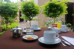 a table with cups and plates of food on it at Benitez Hostería in Calilegua