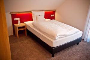 Hotel Brauhaus Stephanus في كوسفلد: سرير مع اللوح الأمامي الأحمر في الغرفة
