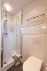 a white bathroom with a shower and a toilet at Hotel Garni "Zur Alten Post" in Willingen +52 photos