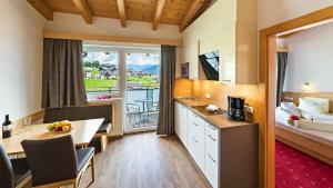 a hotel room with a kitchen and a large window at Apart-Hotel Bergkönig in Fiss