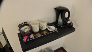 a black shelf with two cups and a coffee maker at Bay Lodge in Birchington