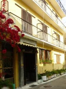 um edifício amarelo com varandas e flores numa rua em Europe Hotel em Corfu Town
