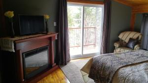 um quarto com uma lareira, uma televisão e uma cama em Strong Timbers BnB em Kingsclear