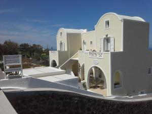 a large white building with a sign in front of it at Kiklamino Sunset Studios in Oia