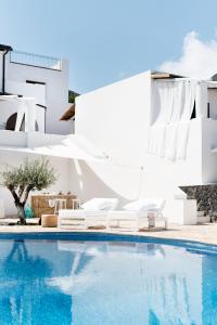 a pool with two white chairs next to a house at Principe Di Salina Boutique Hotel in Malfa