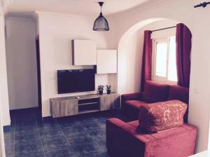 ein Wohnzimmer mit einem roten Stuhl und einem TV in der Unterkunft Rosales Apartment with balcony by Centrall alquileres turísticos in Nerja