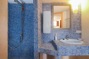 Un baño con azulejos azules, lavabo y espejo. en Loma Los Pelones 78, en Viñuela