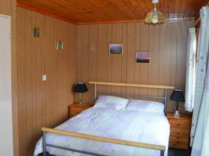 a bedroom with a bed and a wooden wall at Faichemard Farm Chalets in Invergarry