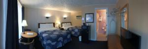 Cette chambre comprend 2 lits et une table. dans l'établissement Moonlite Motel, à Niagara Falls