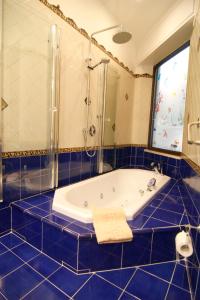 Hotel Due Torri في أَجيرولا: حمام من البلاط الأزرق مع حوض استحمام ودش