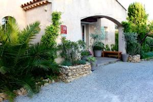 ein Haus mit einer Bank und Pflanzen davor in der Unterkunft Hotel Les Oliviers in Draguignan