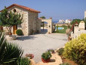 a stone building with a courtyard with plants and flowers at Villa Valentine in Hersonissos