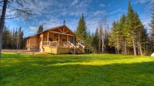 a log cabin in the middle of a grass field at Le St Bernard - Les Chalets Spa Canada in La Malbaie