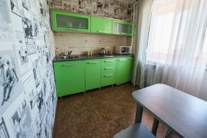 una cocina verde con armarios verdes y una mesa en Apartment Pink on Tereshkovoy 10/5 en Oremburgo