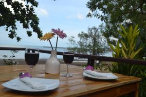 a table with two glasses of wine and a vase with flowers at Baan Chid Talay in Ko Chang