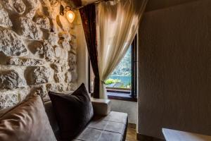 um quarto com uma parede de pedra, um sofá e uma janela em Hill Apartments em Kotor