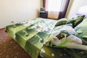 Una cama con una manta verde con flores. en Central Light Apartment en Oremburgo