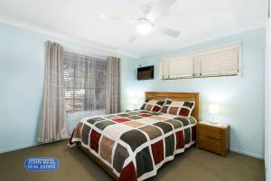 a bedroom with a bed and a window at Beachside Holiday Home in Redcliffe