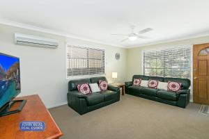 a living room with two leather couches and a tv at Beachside Holiday Home in Redcliffe