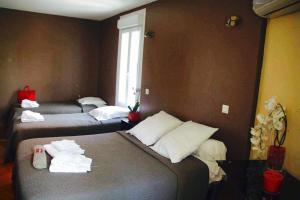 a hotel room with three beds and a window at L'Avenue in Agde