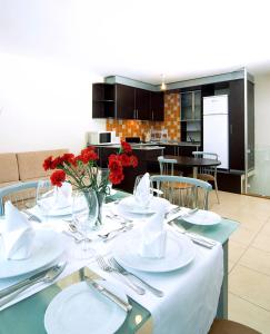 Side Garden Residence في سيدي: طاولة طعام عليها صحون بيضاء وورود حمراء