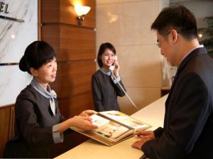 Un uomo e una donna in piedi a un tavolo con un uomo al telefono di Kao Yuan Hotel - Zhong Shan a Taichung