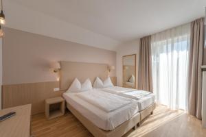 een slaapkamer met een groot bed en een groot raam bij Tirolerin Garni Hotel in Termeno