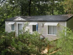 a small white house in the middle of trees at Camping Hurongues in Pomeys +26 photos