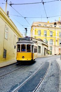 a yellow trolley car driving down a street at Best apartment in Baixa-Chiado in Lisbon