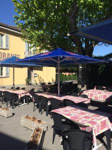 eine Gruppe von Tischen und Stühlen mit blauen Sonnenschirmen in der Unterkunft Ristorante Bironico in Bironico