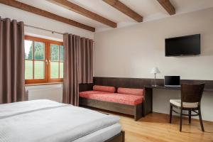 um quarto com uma cama, uma secretária e uma televisão em Aneta Hotel & Restaurant em Vítkovice