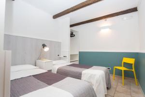 a room with two beds and a yellow chair at B&B Il Viottolo in Noci