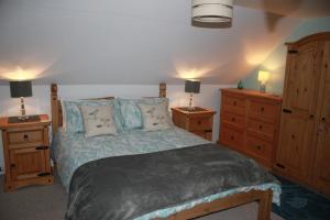 a bedroom with a bed with two dressers and two lamps at Dunshee in Dunvegan