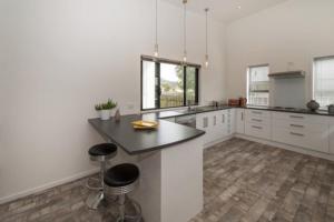 a kitchen with white cabinets and a black counter top at Trendy Bungalow in the Heart of Rotorua in Rotorua