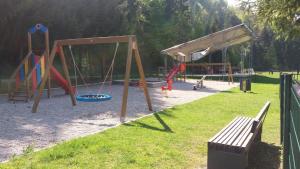 um parque infantil com baloiços e um banco num parque em Apartma Gracner em Bled