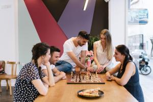 un grupo de personas sentadas alrededor de una mesa jugando ajedrez en Cocoon City Hostel en La Canea