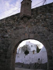 an arch in a stone wall with a brick tower at Casa da Silveirinha in Marvão