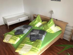 a bed with green sheets and pillows in a room at Haus Johanna in Lechbruck