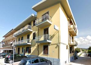 un edificio amarillo con balcones y coches estacionados frente a él en Domo - Guest-House Il Nespolo Fiorito, en Orosei