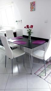a dining room table with white chairs and a vase with flowers at Apartment Luna in Dubrovnik