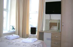 a bedroom with a bed with a television and a dresser at Harrington Guest House in Newquay