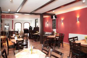 a restaurant with tables and chairs and red walls at Pension La Cascina in Tuttlingen